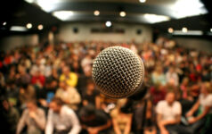 Webinar: Staff up for a new compliance era A mic in front of a packed theater.