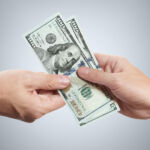 Hands sharing dollars on gray background.