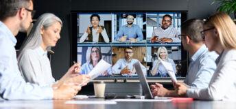 Global corporation online videoconference in meeting room with diverse people sitting in modern office and multicultural multiethnic colleagues on big screen monitor. Business technologies concept.