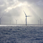 A beautifully lit scene with sunbeams on an offshore wind farm turbine.