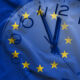 Double exposure of clock and blue flag of European Union