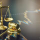 A courtroom gavel and golden scales of justice on a financial analysis chart, representing legal and economic themes.
