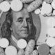 Image of a $100 bill with only Benjamin Franklin's face showing, with the rest of the bill covered by pills.