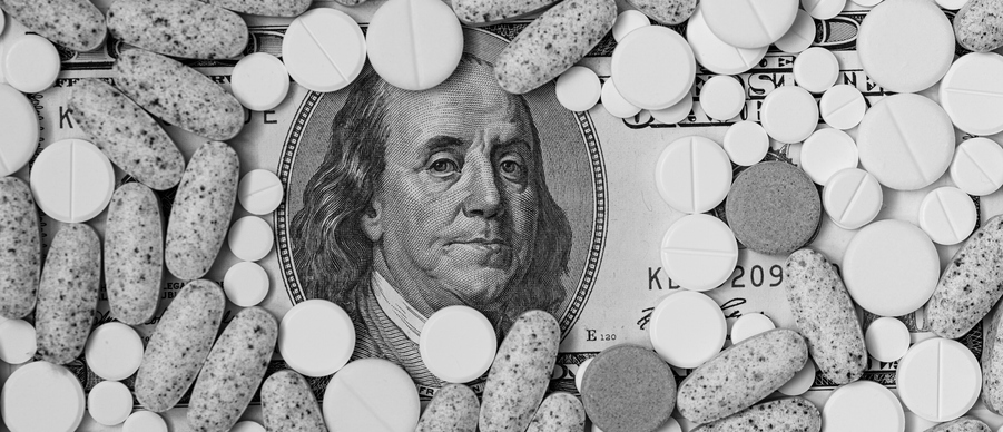 Image of a $100 bill with only Benjamin Franklin's face showing, with the rest of the bill covered by pills.