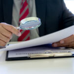 Lawyer or judge use magnifier glass look to the paper for inspection examination to the law case
