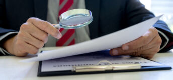 Lawyer or judge use magnifier glass look to the paper for inspection examination to the law case
